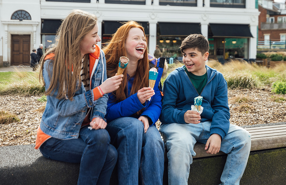 three friends enjoying ice cream on the sea front